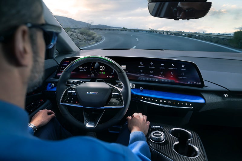 Front View of the 2026 OPTIQ-V Driving Through the Dusk Utilizing its Headlights | Gilleland Cadillac in St Cloud MN