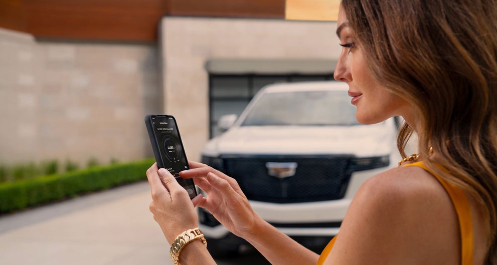 lady checking her mobile with a Cadillac vehicle background | Gilleland Cadillac in St Cloud MN